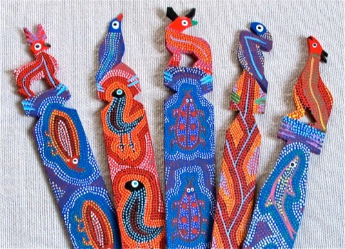 Intricately painted wooden bookmarks topped with colorful creatures.