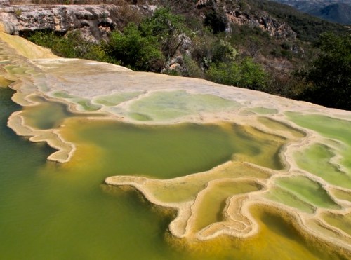 Green tinged water in pool on side of cliff.