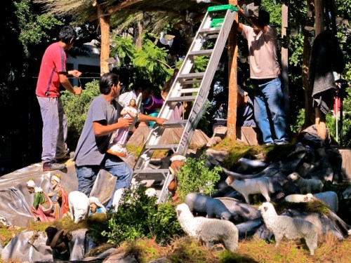 Workman about to carry an angel mannequin up a ladder.