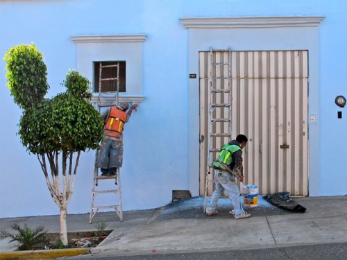 2 painters painting a pale blue building