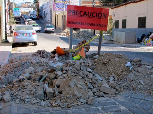 Pile of torn up street rubble in street, with red sign:  Precaución - Hombres Trabajando