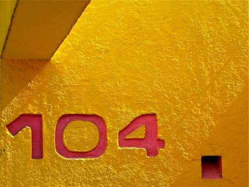 Magenta numbers 104 against bright yellow wall