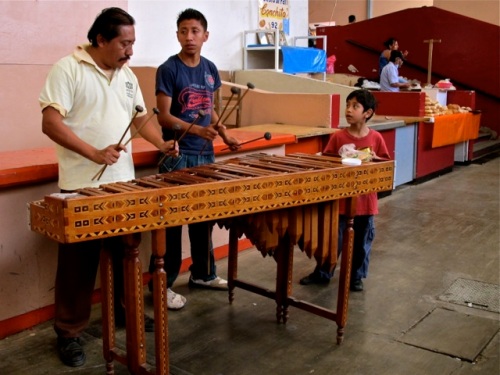 Man, teenage boy, and young boy playing marimba
