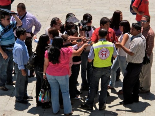 Representative of the Proteccíon Civil Municipal de Oaxaca in a yellow vest giving a press conference.