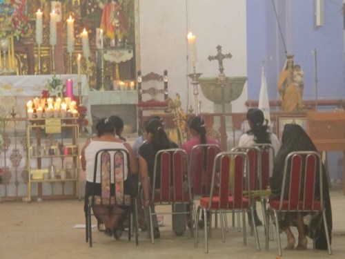 7 women sitting in chairs in front of an altar, in the haze of incense. 