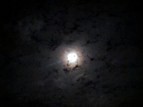 Full moon with halo shining from behind clouds  
