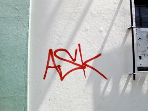 The word "ASK" written on white wall with light green trim on left
