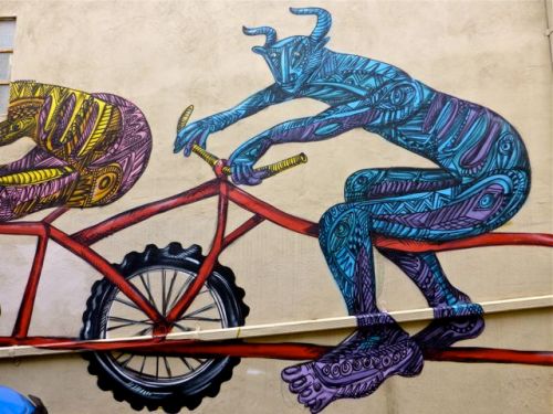 Painted horned creature riding a bike.