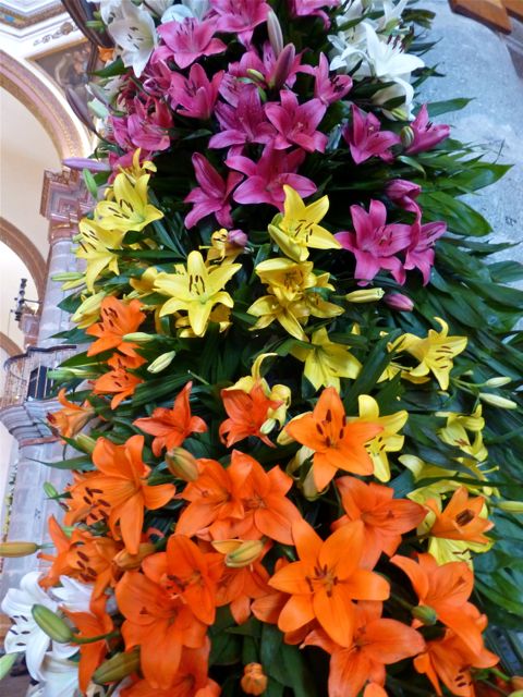Close-up of orange, yellow, and lavender lilies covering a pillar