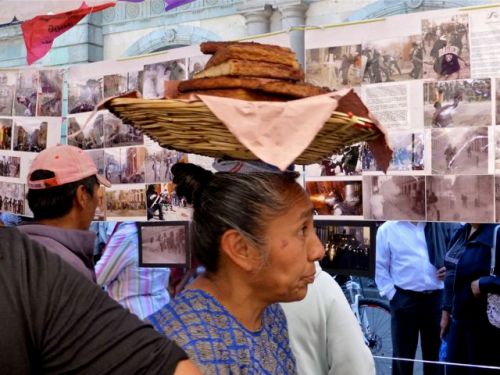 Women looking at photos, with a basket of sliced bread on her head.