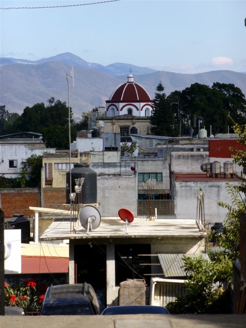 Looking over rooftops at red domed church in mid distance and mountains in background