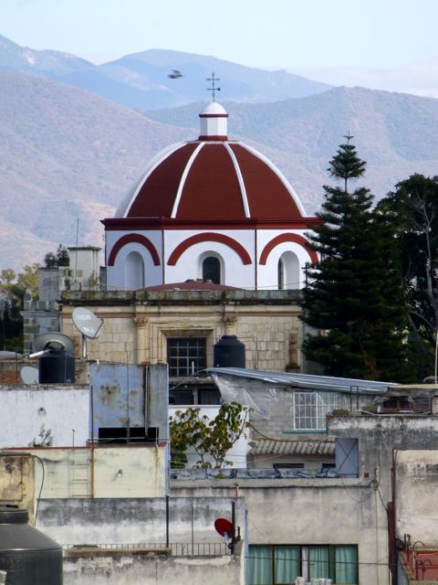Looking over rooftops at red domed church in mid distance and mountains in background