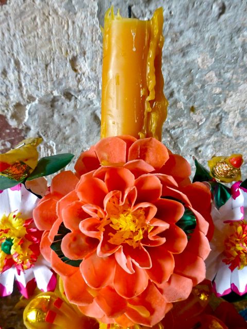 Candle surrounded by wax flowers.