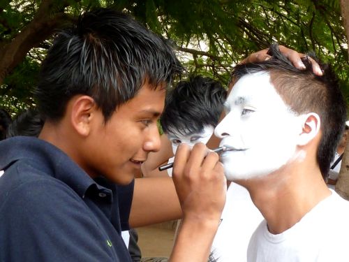 Young man painting face of another young man