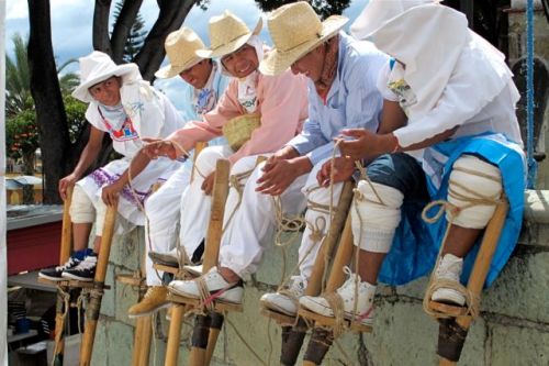 5 stilt dancers sitting on a ledge.