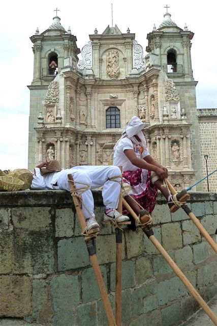 Stilt dancers sitting on ledge, Basilica of Soledad in background