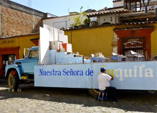 Man painting a banner on a flatbed truck