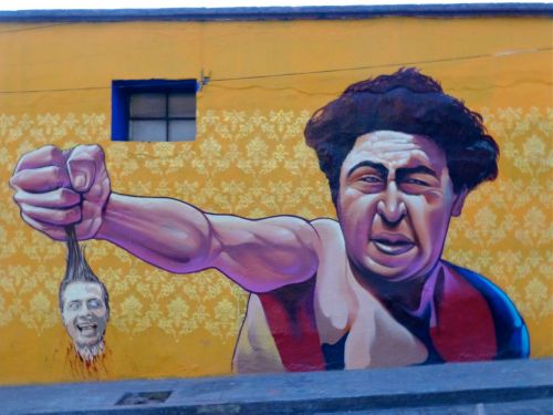 Mural on wall of giant man holding small Peña Nieto head by his hair
