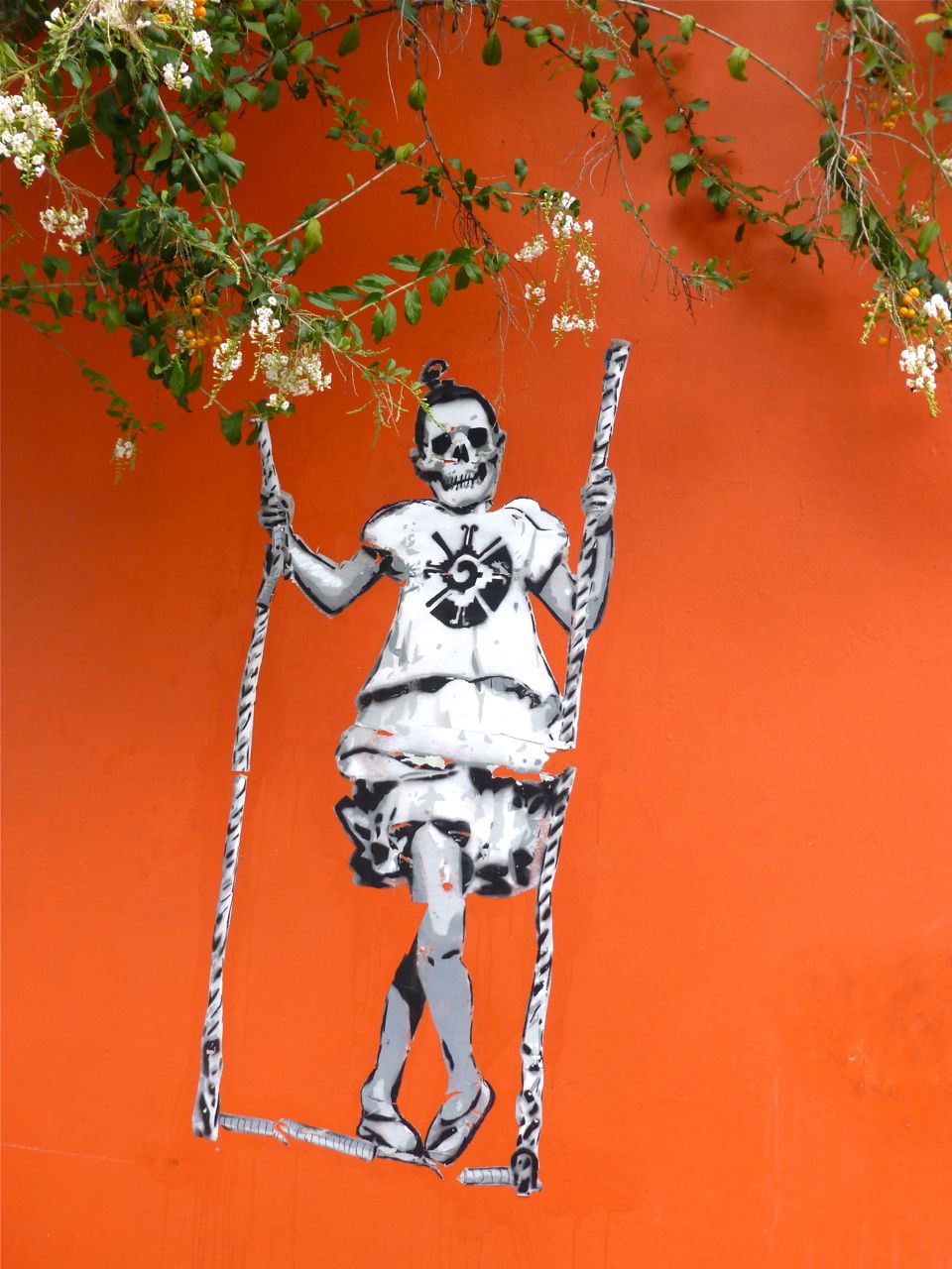 Skeleton on swing painted on orange wall