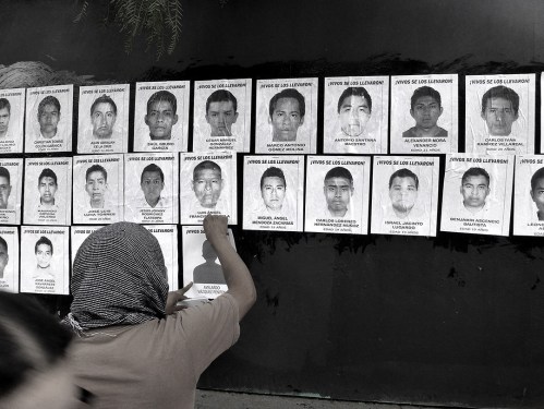 Person putting photos of missing students on wall